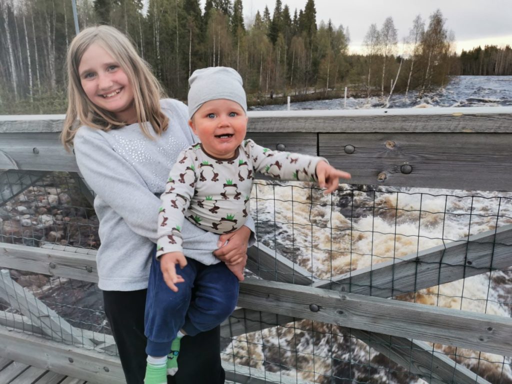 Isosiskon sylissä oleva vauva osoittaa sormellaan eteenpäin.